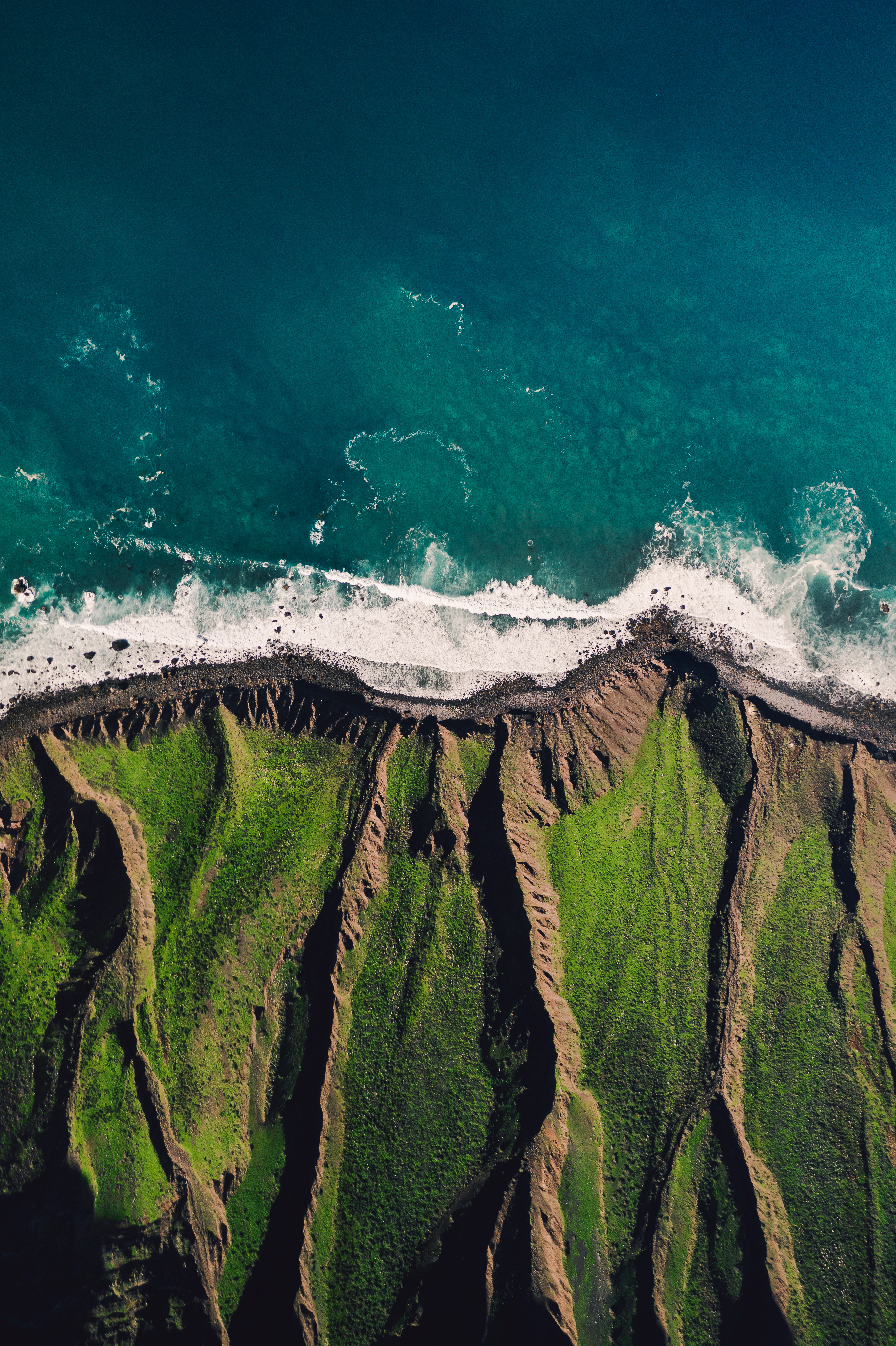 waves crashing on the edge of a grassy cliff