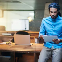Man sitting on a desk reading information